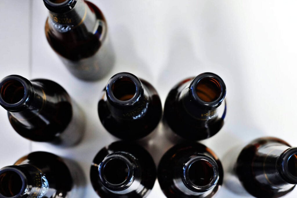 Array of empty alcohol bottles indicating symptoms of alcohol addiction - NOLA Detox