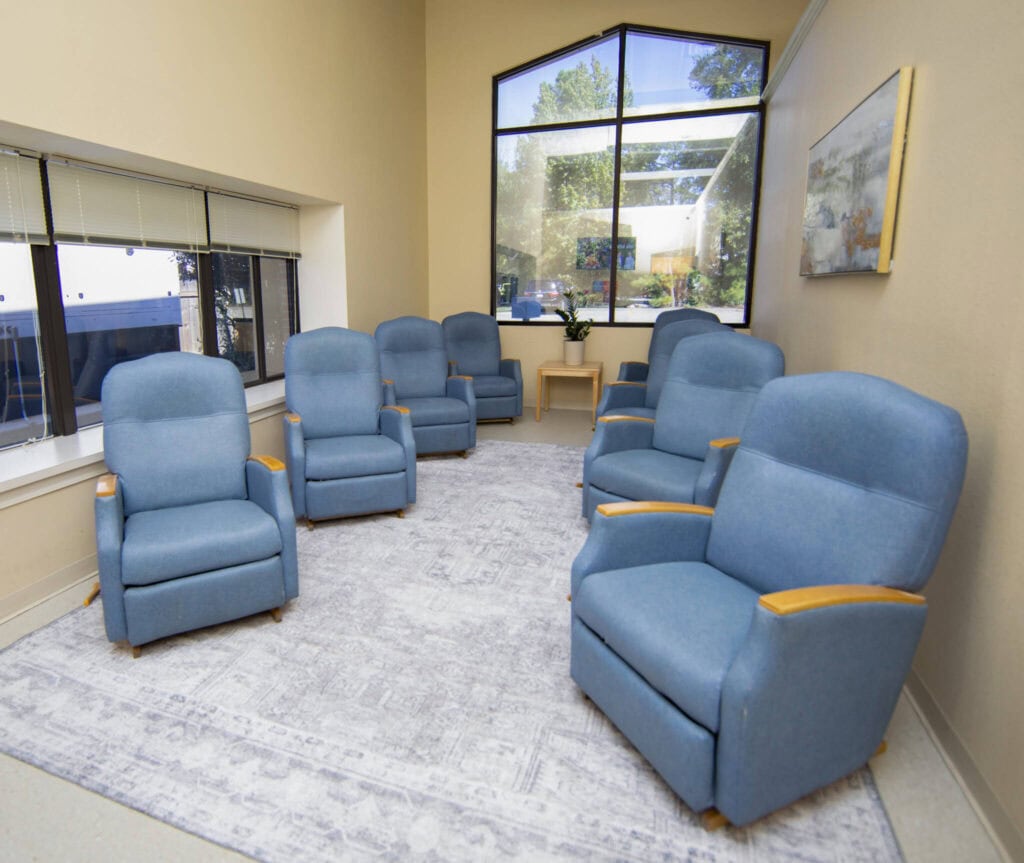Comfortable blue recliner chairs in a waiting room with large windows and artwork.