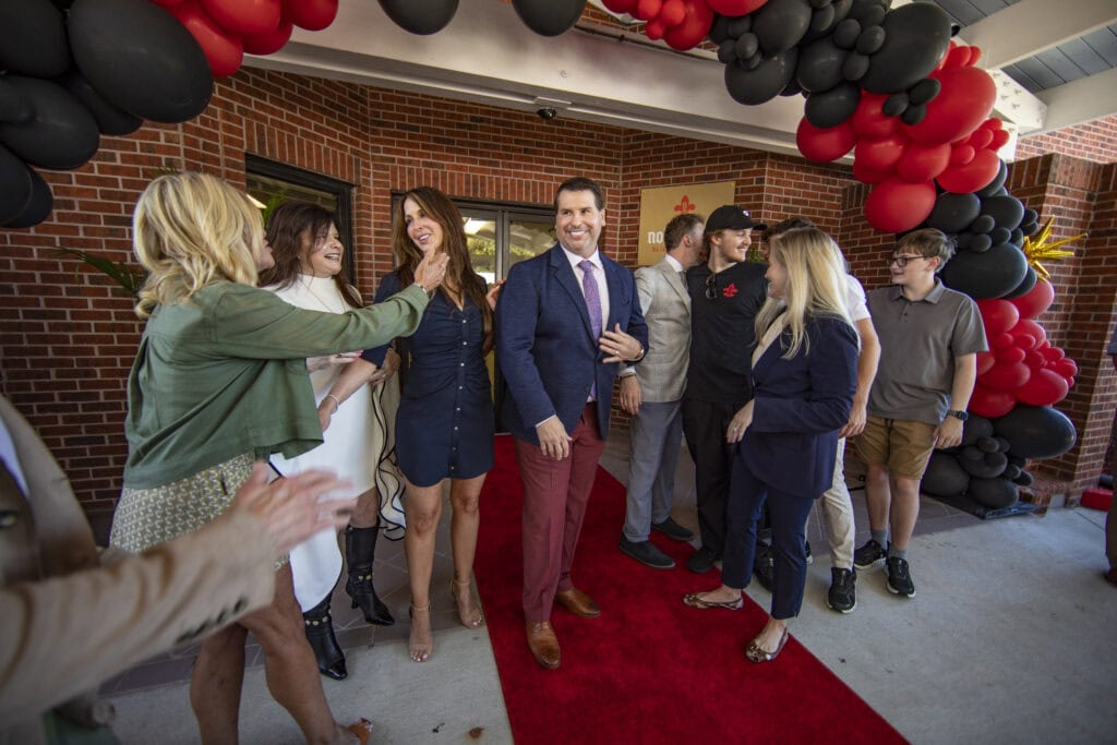 Group of people celebrating at NOLA Detox event with balloons and red carpet.