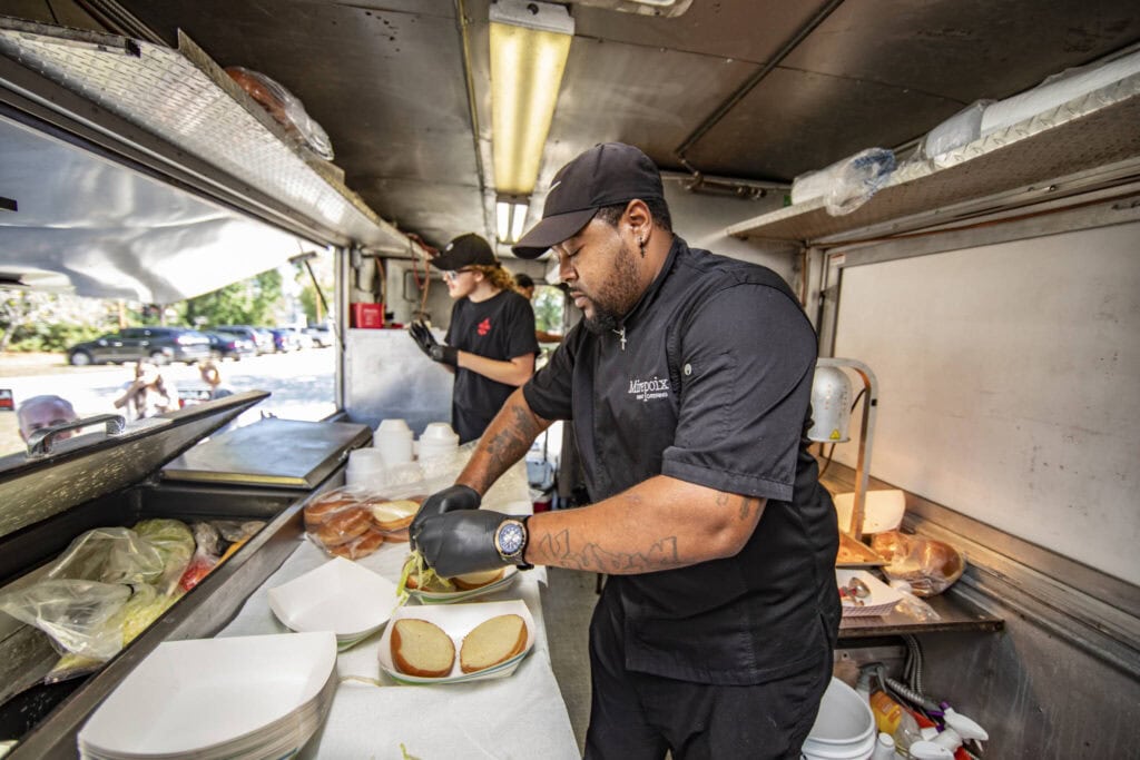 Chef preparing sandwiches in a food truck for NOLA Detox.