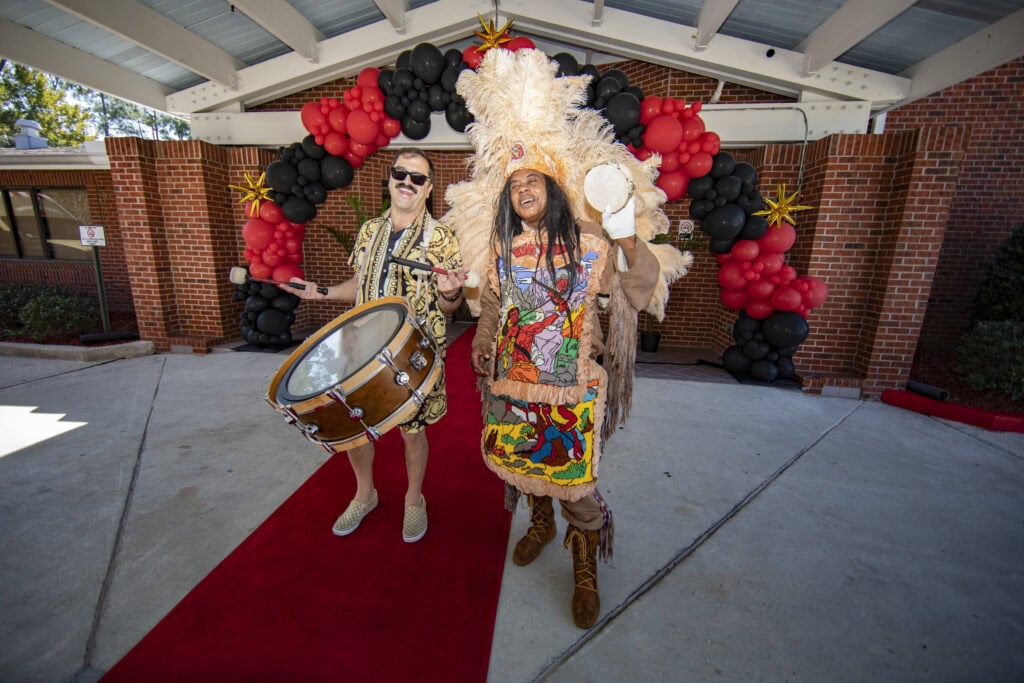 People in colorful traditional costumes celebrating at NOLA Detox event.
