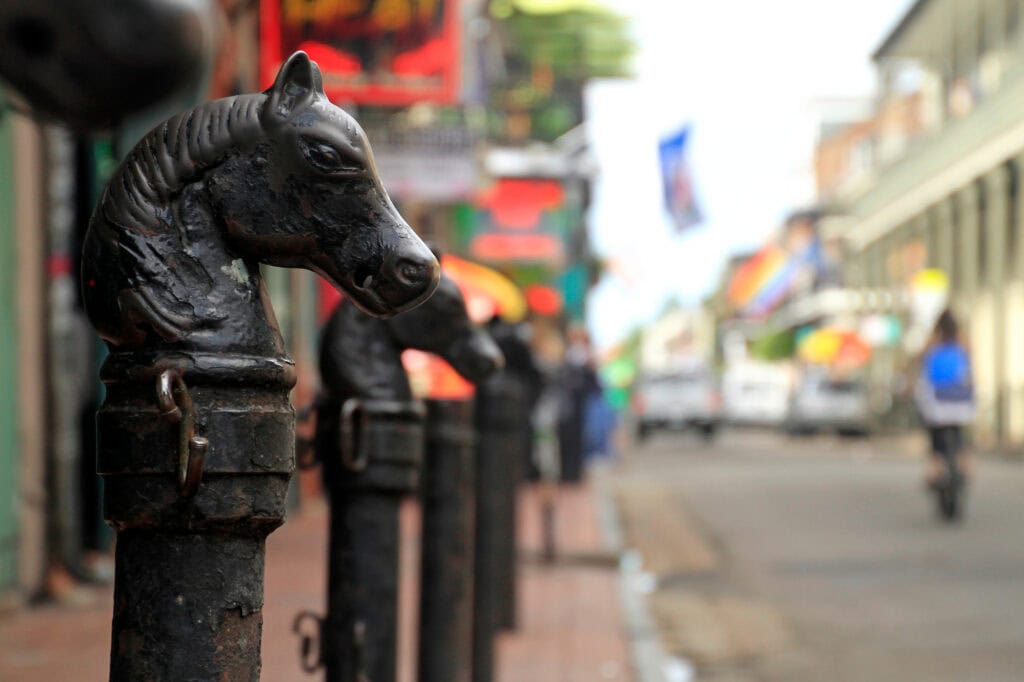 Black horse head sculpture on a city sidewalk in New Orleans.
