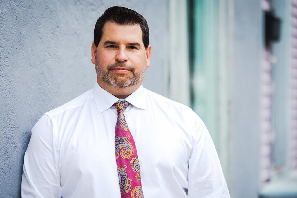 Professional man in white shirt and colorful tie outside building.