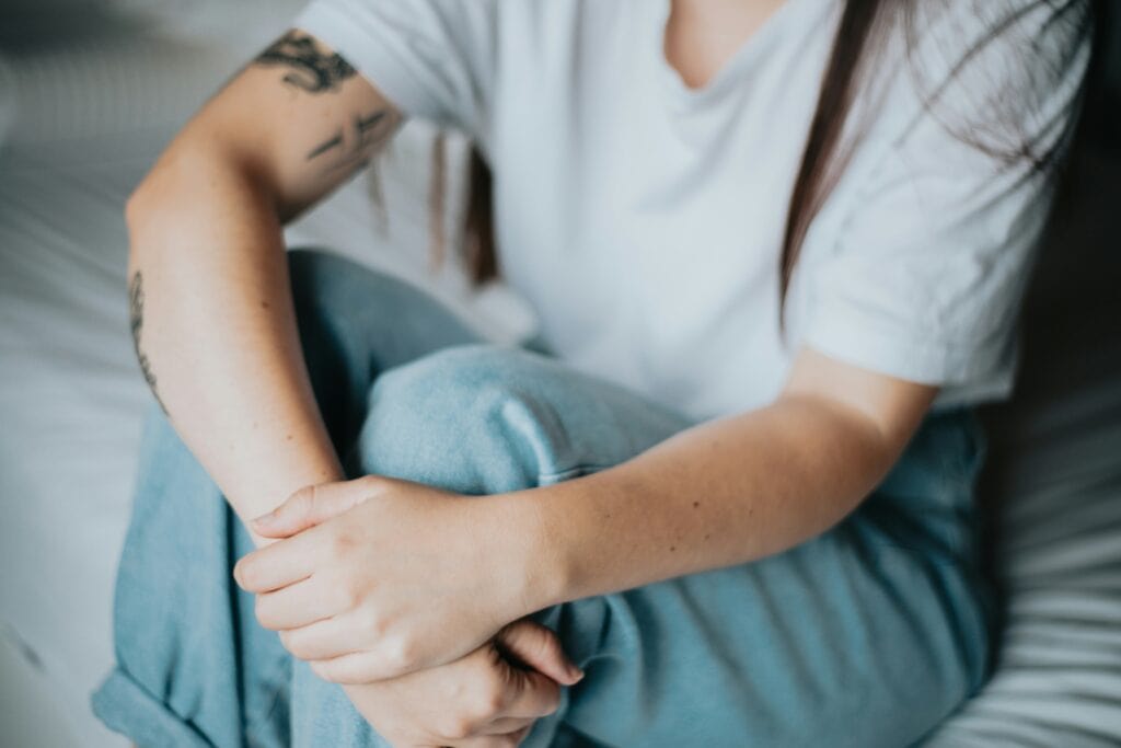 Young woman holding her knees, showing signs of anxiety or depression.