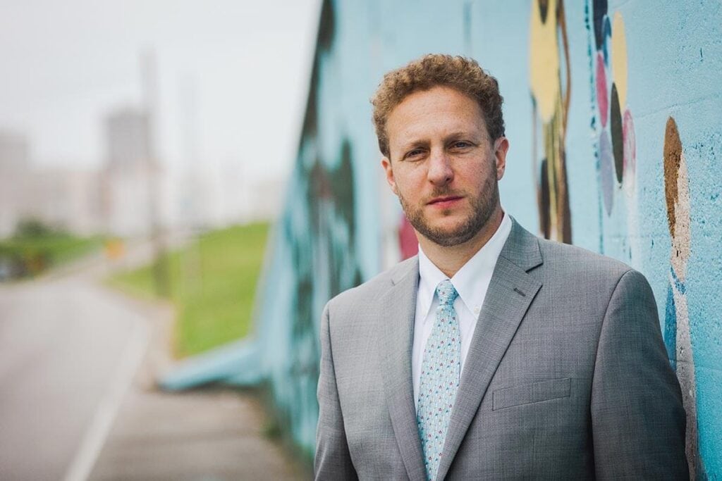 Professional man in suit standing by colorful graffiti wall in New Orleans.