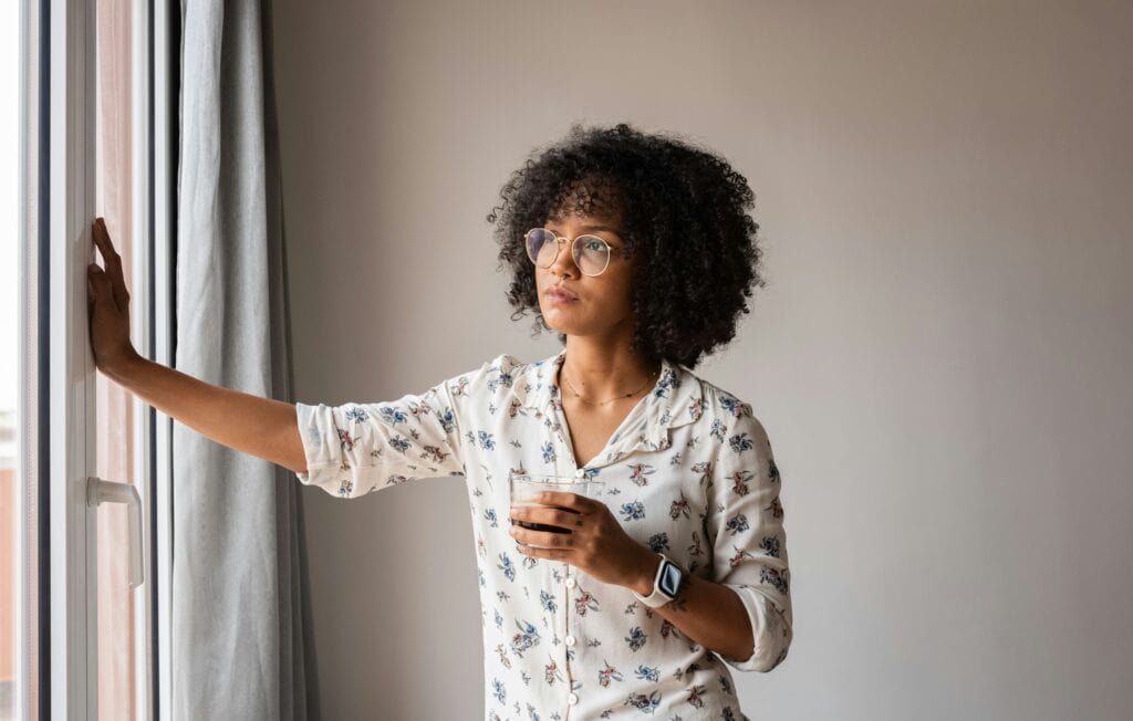 Woman gazing out window, contemplating, seeking relief from anxiety and depression.