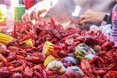 Fresh crawfish, corn, and vegetables at a seafood boil event.