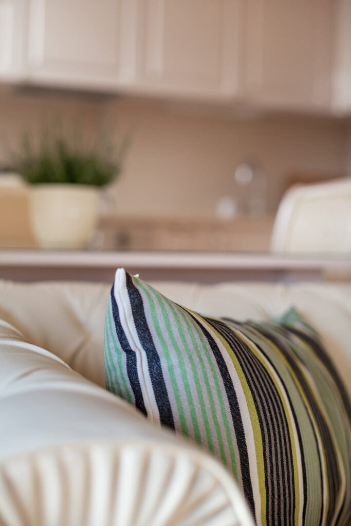 Cozy living room with striped pillow and blurred background kitchen.